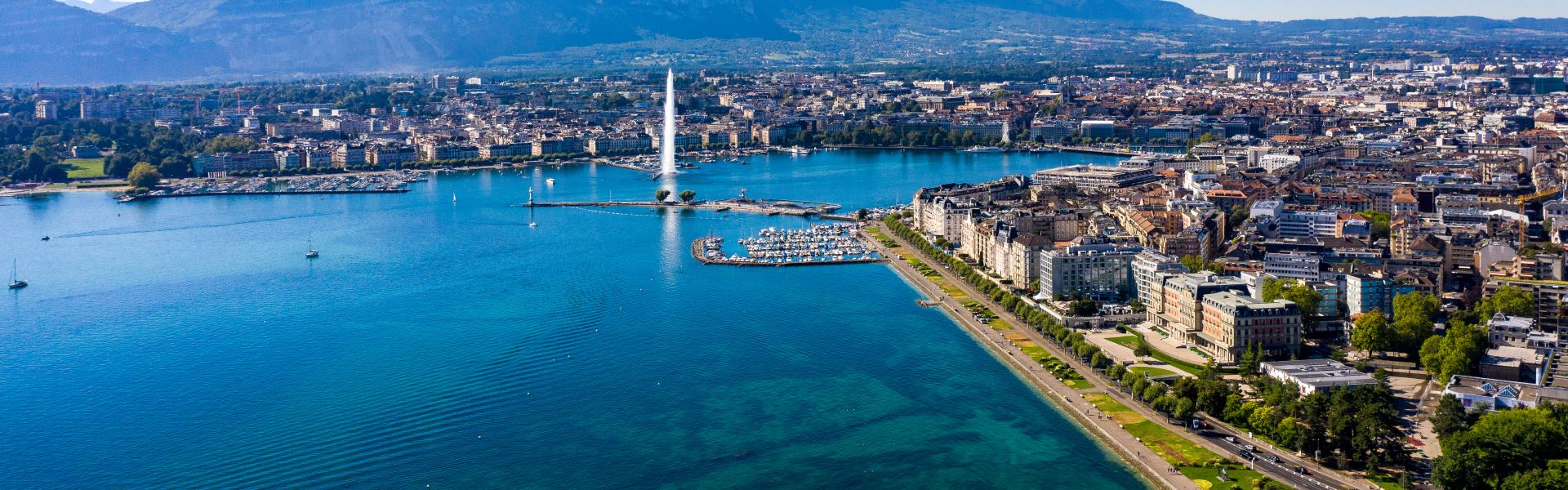 Panorama du lac de Genève avec son jet d'eau et les façades de la ville se reflétant dans le lac